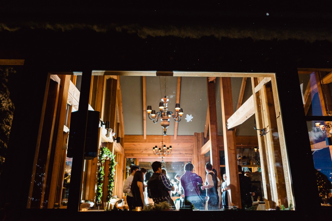 Crowd dancing in the big glass window reception hall after a snow storm for the winter wedding in edge water lodge, Whistler