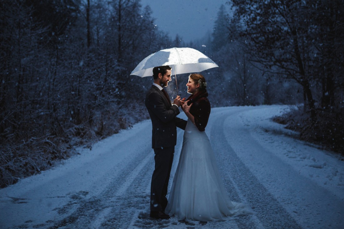 shinning umbrella with shinning flakes while the newly weds walking in the middle of the road