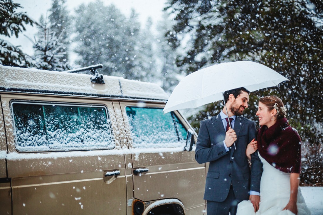 groom holding umbrella while holding the bride for their promenade after the outdoor ceremony for their destination wedding in whistler