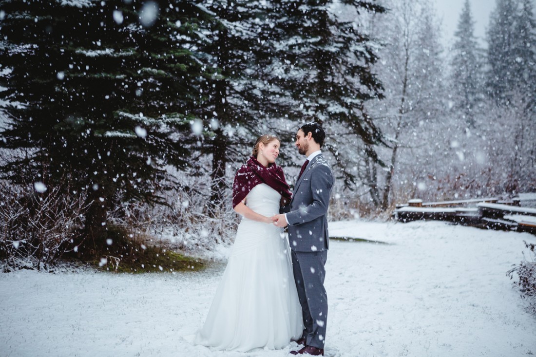 couple walking in the forest under the snow in whistler for their destination wedding
