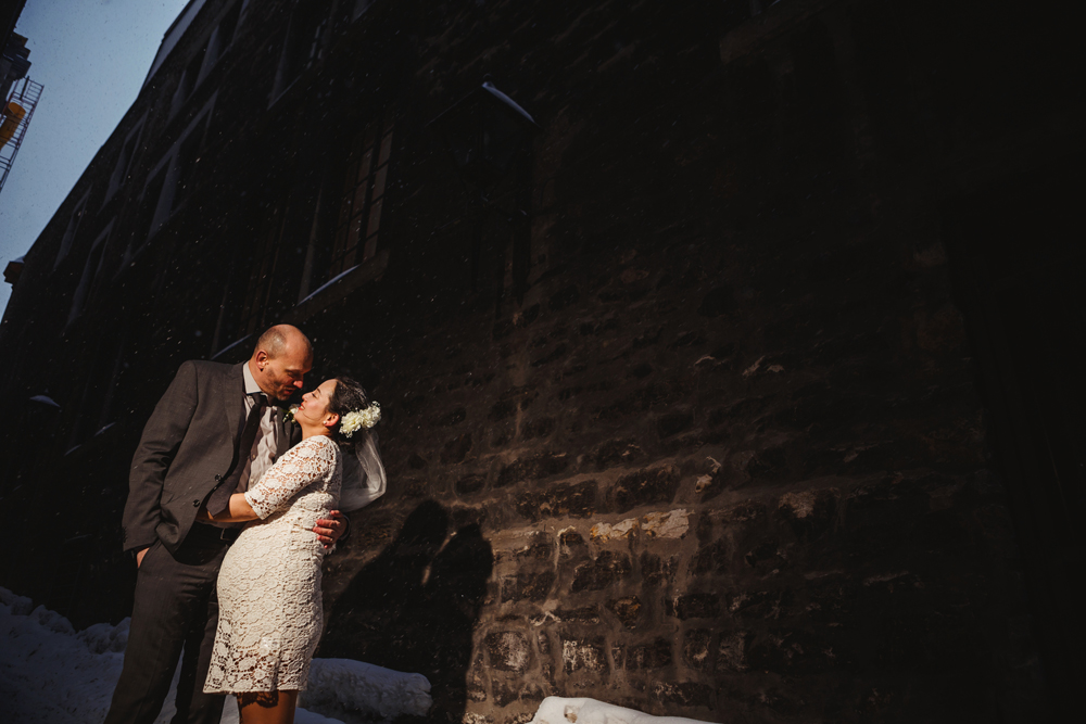 bride and groom looking at each other after the ceremony under snow in an alley of old port, montreal