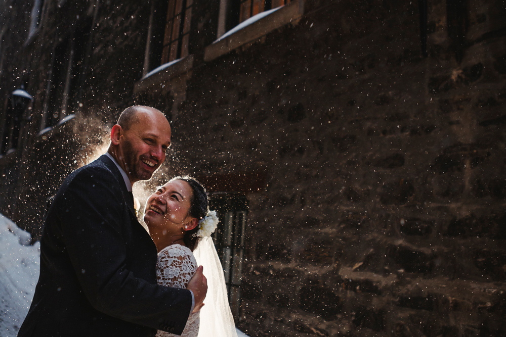 bride and groom having a fun moment with snow splashing after the ceremony under snow in an alley of old port, montreal